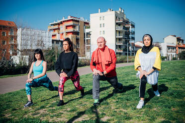 Calisthenics-Kurs in einem Fitnessstudio im Freien, junge Frauen und ein Mann üben die Yoga-Position eines Kriegers - CUF51963