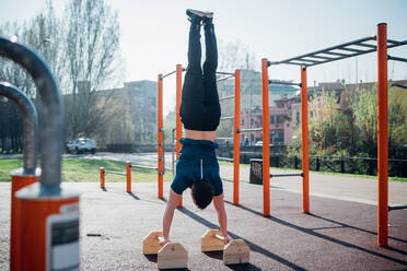 Gymnastik im Freien, junger Mann macht Handstand an einem Trainingsgerät, Rückansicht - CUF51970
