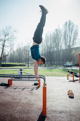 Gymnastik im Freien, junger Mann macht Handstand am Barren - CUF51985