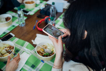 Young woman photographing meal at cafe table, over shoulder view - CUF51993