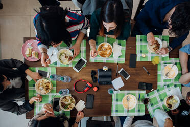 Young male and female business team sharing meal at cafe table, overhead view - CUF51994