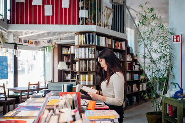 Junge Geschäftsfrau beim Stöbern in Büchern in einer Buchhandlung - CUF52012