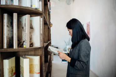 Young businesswoman browsing book in bookshop - CUF52017