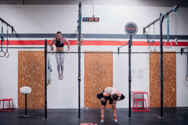 Junge Frau und Mann beim Training, an Übungsstangen im Fitnessstudio - CUF52023