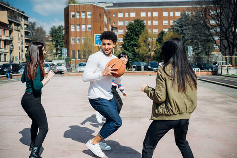 Junge weibliche und männliche erwachsene Freunde spielen Basketball auf dem Stadtplatz, lizenzfreies Stockfoto