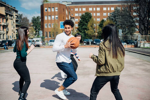 Junge weibliche und männliche erwachsene Freunde spielen Basketball auf dem Stadtplatz - CUF52069