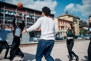 Junge weibliche und männliche erwachsene Freunde spielen Basketball auf dem Stadtplatz - CUF52070