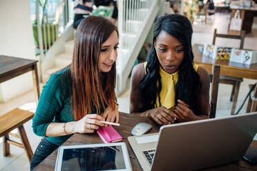 Young businesswomen remote working, looking at laptop in cafe - CUF52099