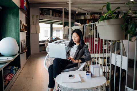 Junge Geschäftsfrau mit Laptop in einer Buchhandlung, lizenzfreies Stockfoto