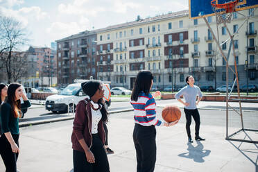 Junge weibliche und männliche erwachsene Freunde spielen Basketball auf dem Stadtplatz - CUF52115