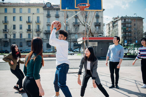 Junge weibliche und männliche erwachsene Freunde spielen Basketball auf dem Stadtplatz - CUF52116