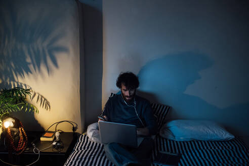 Bärtiger junger Mann mit Laptop im Bett - CUF52120