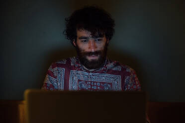 Bärtiger junger Mann benutzt Laptop zu Hause - CUF52149