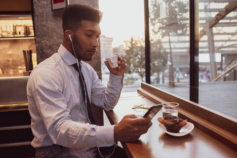 Geschäftsmann mit Smartphone zur Teezeit im Café, lizenzfreies Stockfoto