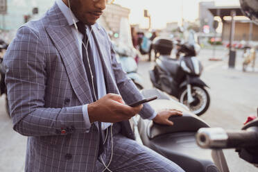 Businessman using smartphone by motorcycle - CUF52173