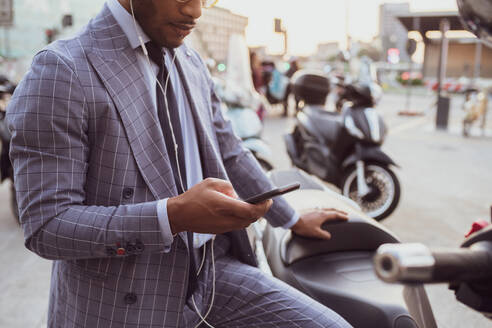 Geschäftsmann benutzt Smartphone auf dem Motorrad - CUF52173