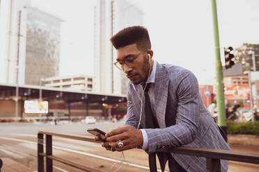 Businessman using smartphone on pavement, Milano, Lombardia, Italy - CUF52175