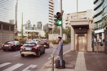 Geschäftsmann wartet am Fußgängerübergang, Mailand, Lombardei, Italien - CUF52178