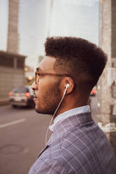 Businessman with earphones on pavement - CUF52180