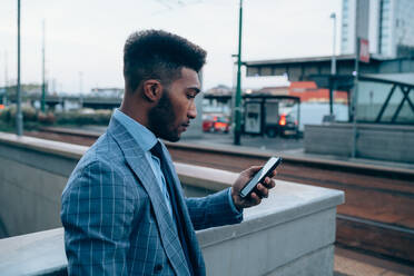 Businessman using smartphone on pavement, Milano, Lombardia, Italy - CUF52182