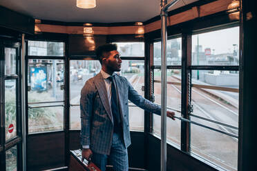 Businessman travelling on tram in city - CUF52183