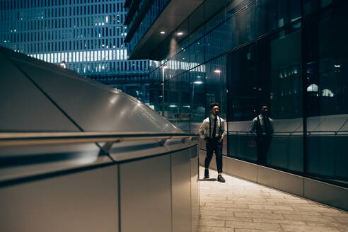 Geschäftsmann geht an einer verspiegelten Wand eines Bürogebäudes vorbei, Mailand, Lombardei, Italien - CUF52203