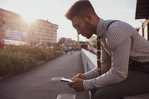 Geschäftsmann mit Smartphone auf dem Bürgersteig, Mailand, Lombardei, Italien - CUF52213