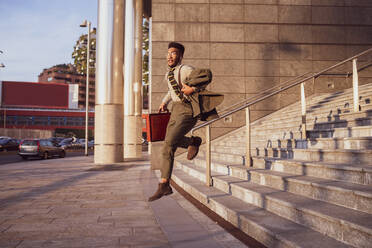 Geschäftsmann springt von der Treppe eines Bürogebäudes, Mailand, Lombardei, Italien - CUF52228