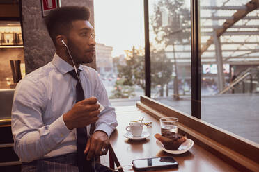 Businessman using smartphone at tea time in cafe - CUF52232