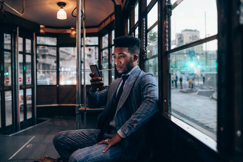 Geschäftsmann benutzt Smartphone in der Straßenbahn in der Stadt - CUF52234