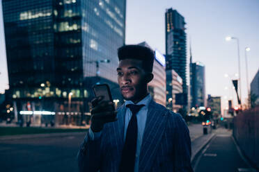 Businessman using smartphone on pavement, Milano, Lombardia, Italy - CUF52239