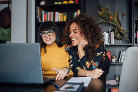 Freunde benutzen Laptop im Heimbüro, lizenzfreies Stockfoto