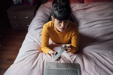 Frau mit Kopfhörern und Laptop auf dem Bett - CUF52270