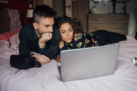 Ehepaar benutzt Laptop auf dem Bett, lizenzfreies Stockfoto