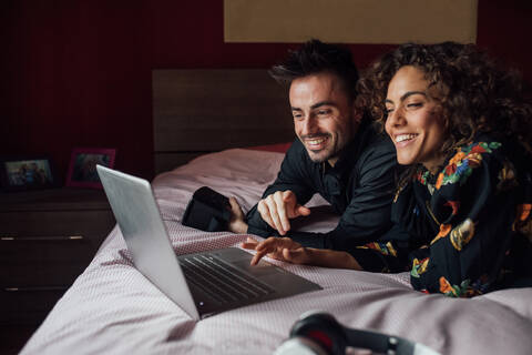Ehepaar benutzt Laptop auf dem Bett, lizenzfreies Stockfoto