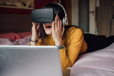 Frau mit VR-Headset auf dem Bett - CUF52280