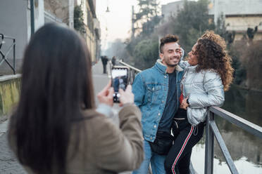 Friends taking photograph by river, Milano, Lombardia, Italy - CUF52287