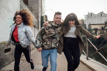 Friends laughing and playing by river, Milano, Lombardia, Italy - CUF52290