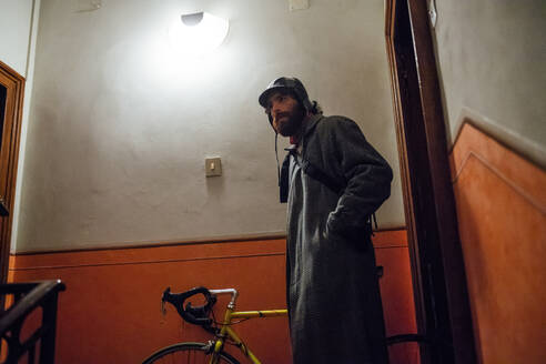 Bärtiger junger Mann verlässt mit Fahrrad das Haus - CUF52323