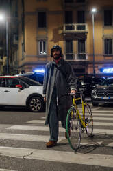 Bärtiger junger Mann auf Fußgängerüberweg mit Fahrrad - CUF52325