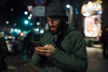 Bearded young man using smartphone on street - CUF52334