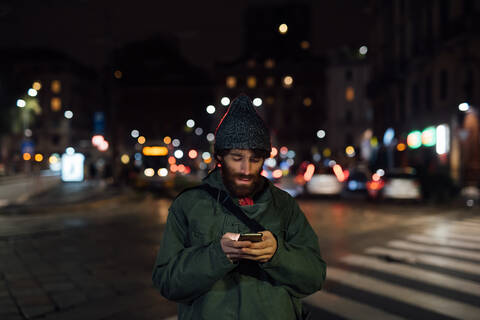 Bärtiger junger Mann benutzt Smartphone auf der Straße, lizenzfreies Stockfoto