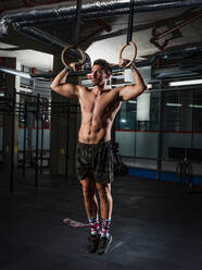 Mann trainiert mit Gymnastikringen in einer Turnhalle - CUF52394