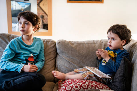 Brothers looking up in disbelief on sofa stock photo