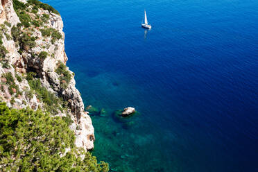 Blick auf das blaue Meer und die Yacht von der Klippe aus, hoher Blickwinkel, Alghero, Sardinien, Italien - CUF52443