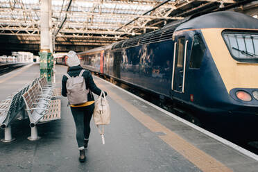 Woman walking to train at platform, Edinburgh, Scotland - CUF52494