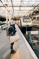 Frau wartet auf dem Bahnsteig eines Bahnhofs, Edinburgh, Schottland - CUF52495