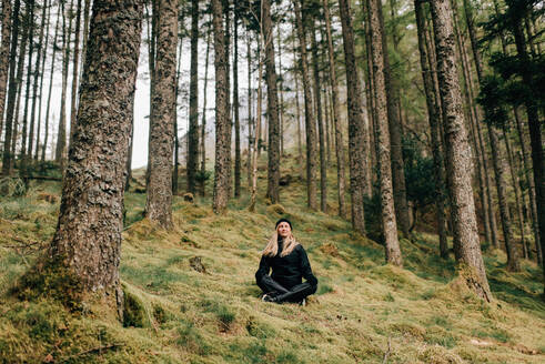 Trekker meditating in forest, Trossachs National Park, Canada - CUF52502