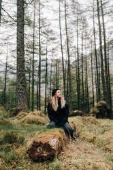 Frau sitzt auf einem Baumstamm, Trossachs National Park, Kanada - CUF52509