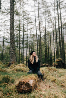 Woman sitting on log, Trossachs National Park, Canada - CUF52509